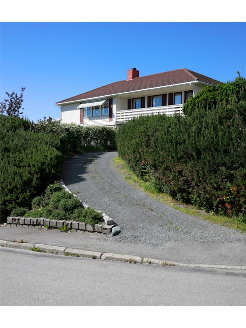 Bildet viser en bakke opp til et hvitt Block Watne-hus.