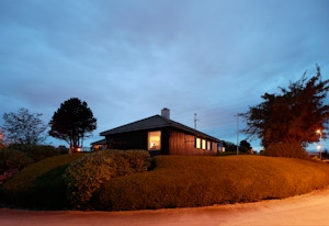 Bildet viser et Obos block watne-hus med hekk rundt huset på kveldstid.
