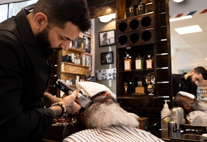 Mannlig frisør barberer skjegget til kunde