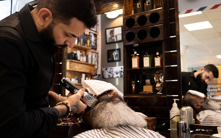 Mannlig frisør barberer skjegget til kunde