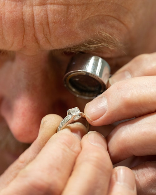 Gullsmed Bjørn Engebretsen ser på en ring gjennom et forstørrelsesglass.