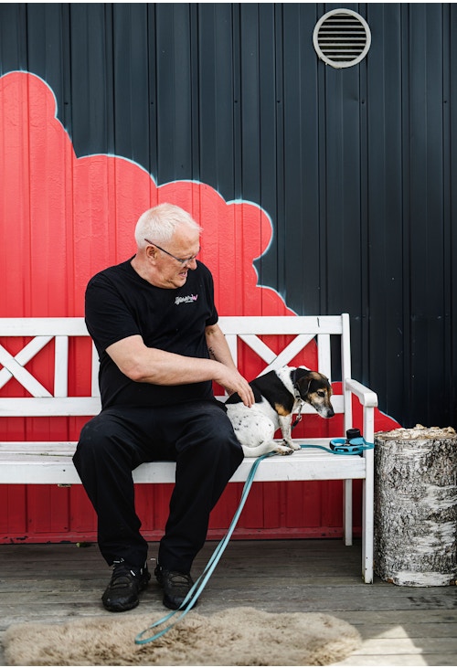 Dominique Deweer, eieren av Codfather på Fornebu, sitter på en benk sammen med hunden sin.