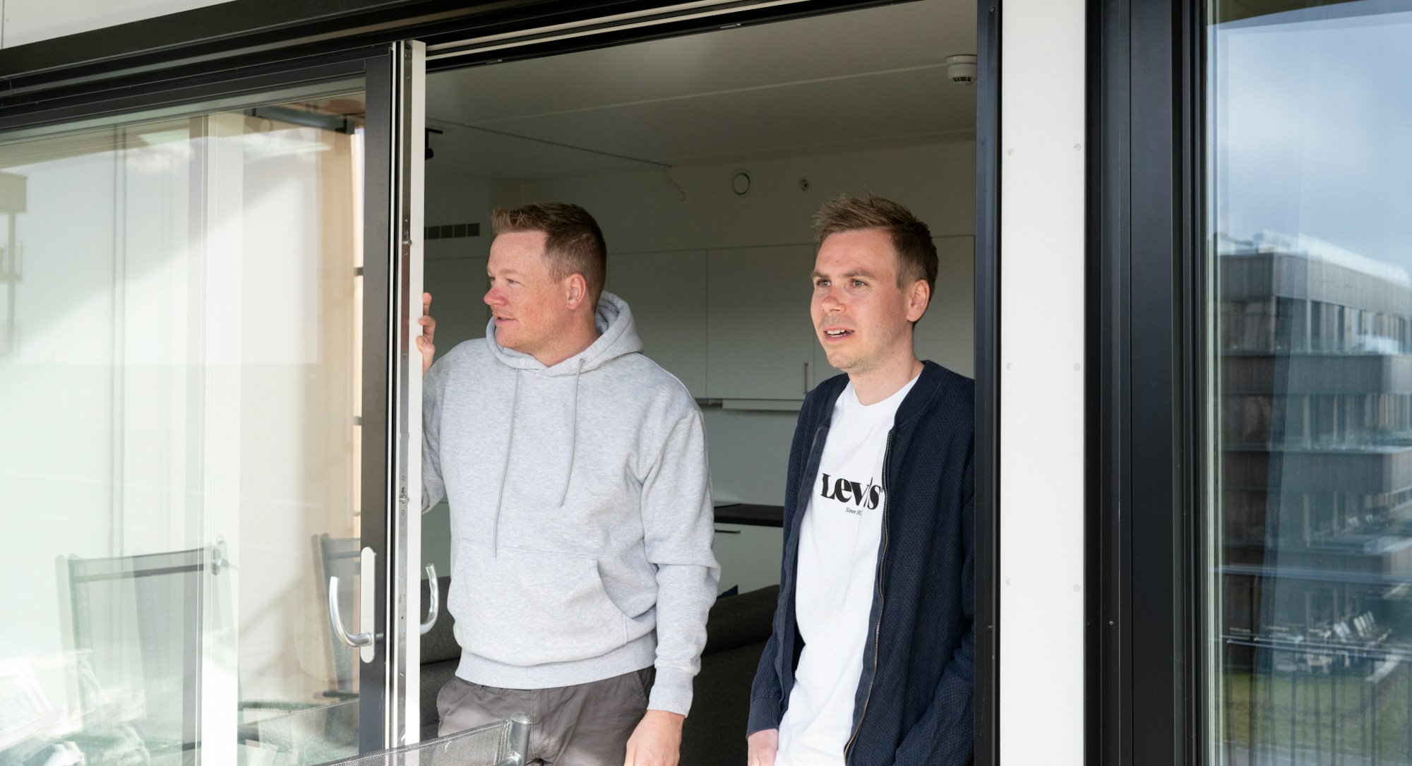 To menn som står i døråpningen til en balkong i Begbyåsen.