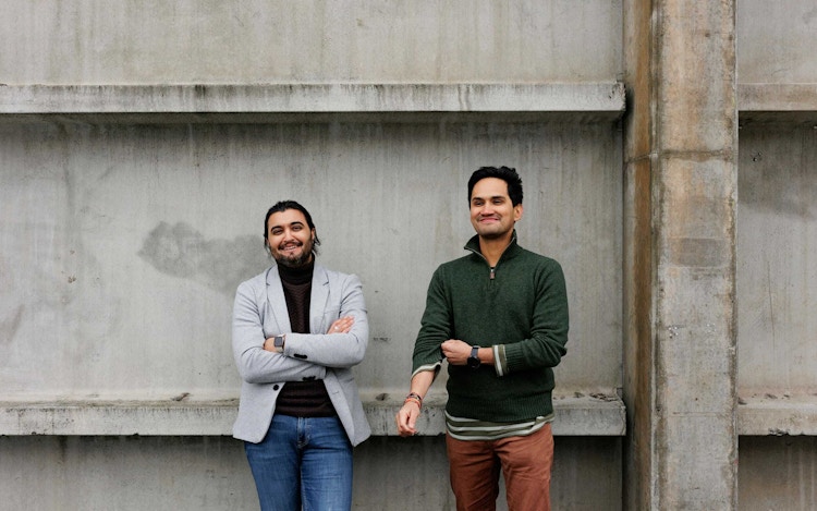 Foto av Mario Vahos og Osman Ilyas foran en betongvegg smilende.