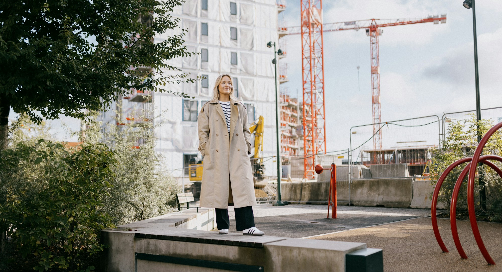 Foto av Brita som står foran byggeområdet på Ulven hvor hun har kjøpt seg leilighet