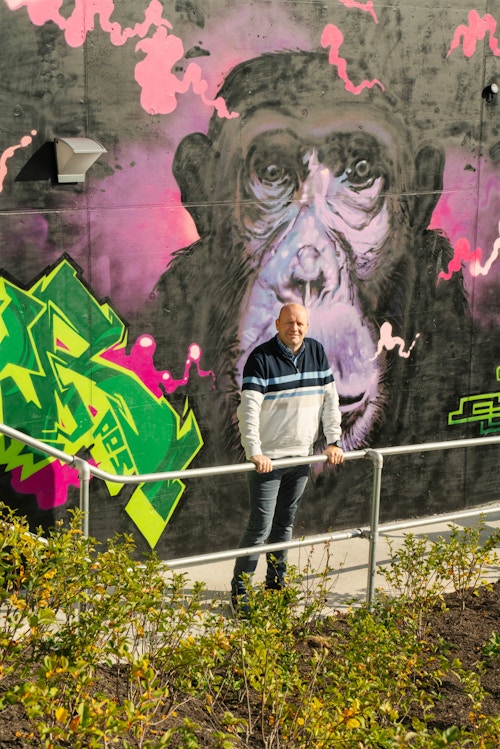 Foto av Ole Morten som står foran en del av grafittiveggen, her av en stor sjimpanse.