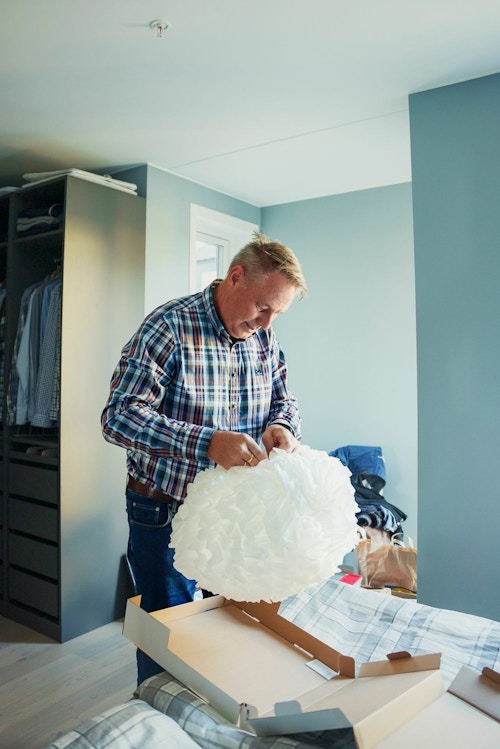 Lars Iver Wiig pakker ut en lampe fra en flytteeske