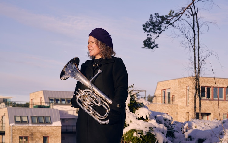 Foto av beboeren Siri i Sandsliåsen ute på vinteren med barytonhornet sitt.