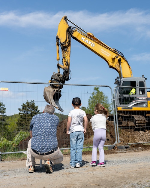 Foto av Tor Helge og barnebarna som ser på en gravemaskin på byggeplassen til Stertebakke Alle.