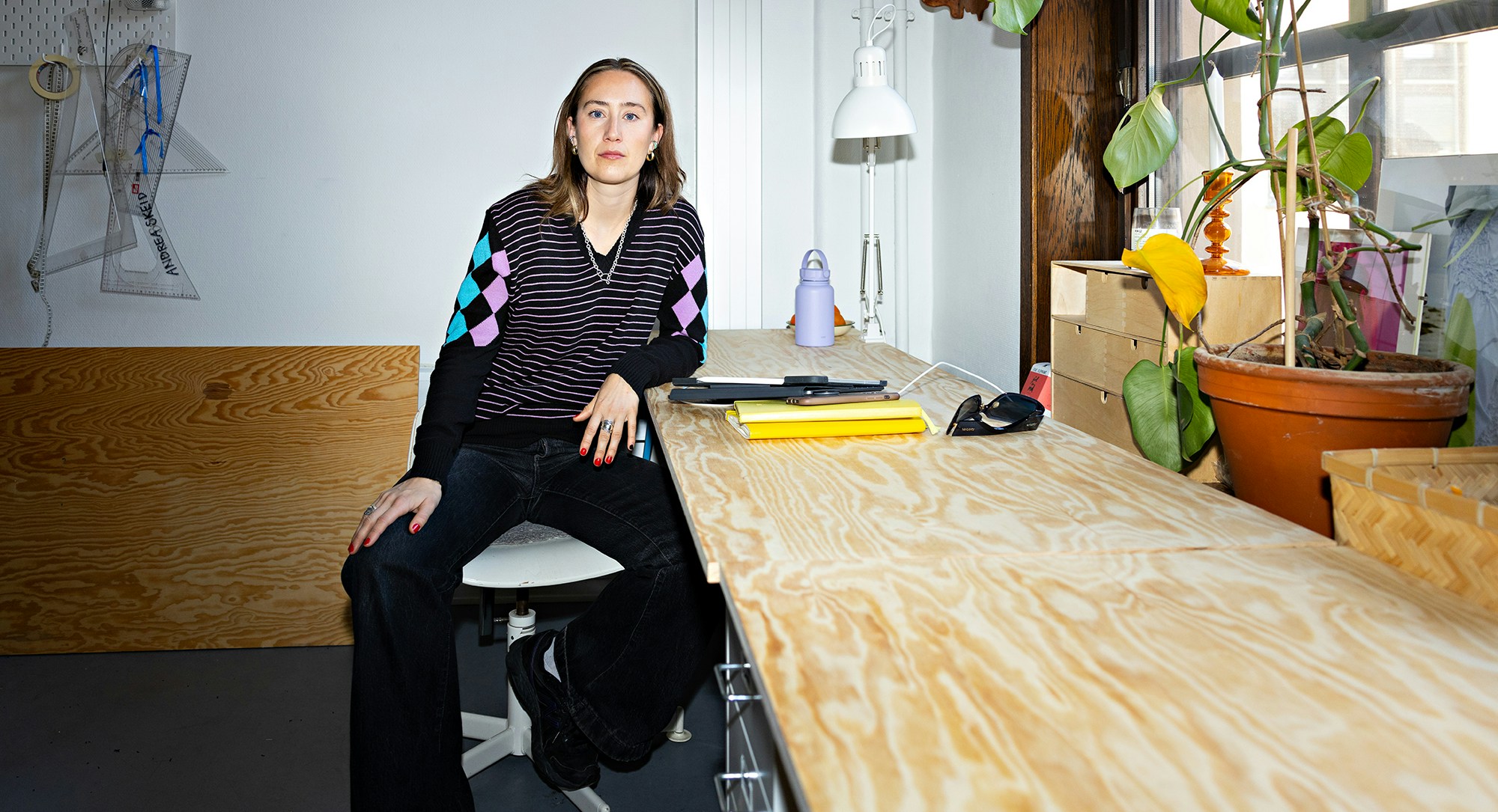 Foto av Alva Brosten som sitter ved arbeidsbenken sin.