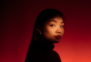 Liggende portrettfoto av Catharina Vu mot mørkerød bakgrunn.