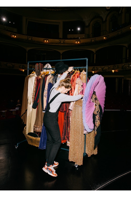 Bildet viser Maja Eline Larssen som triller på et stativ med kostymer på scenen i Nationaltheatret.