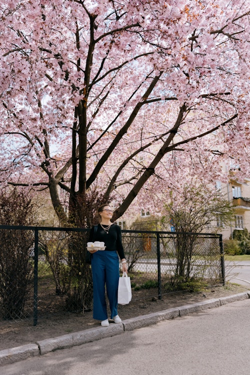 Foto av Vivi Hatlem med kaffe i hånden og under et tre med rosa blader