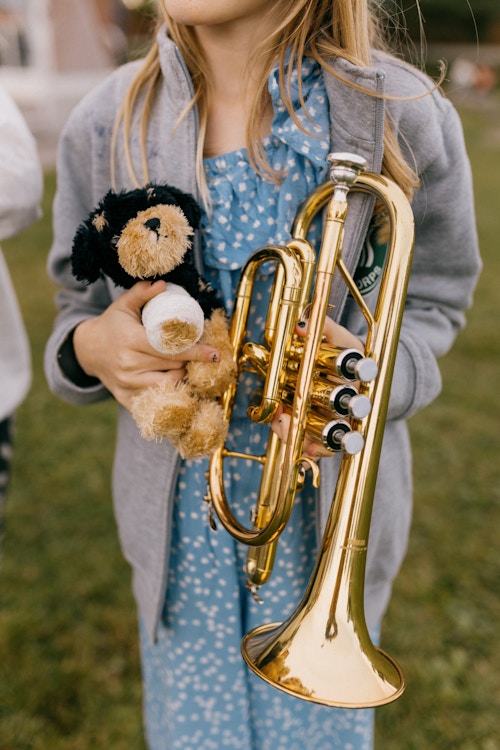 En ung musikant med instrumentet hennes og en bamse.
