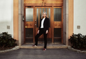 Anne-Kristine Kronborg ved inngangsdøren til en boligblokk.