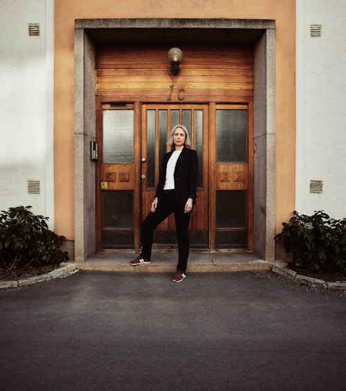 Anne-Kristine Kronborg ved inngangsdøren til en boligblokk.