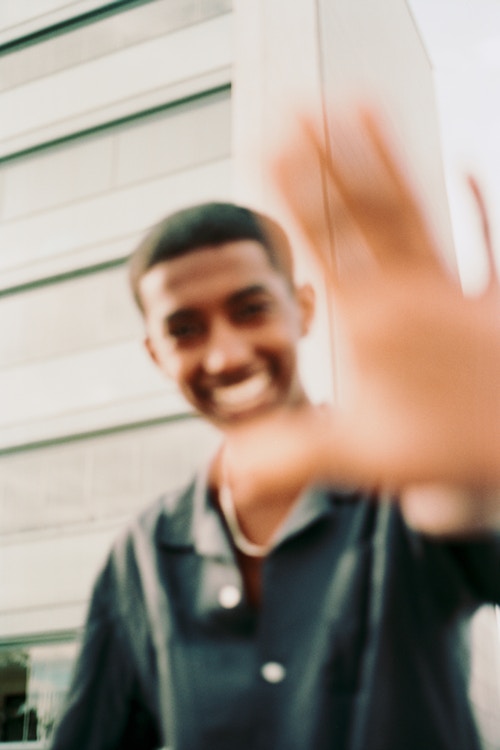 Bilde av rapperen Rambow som smiler og holder opp hånden foran kameraet.