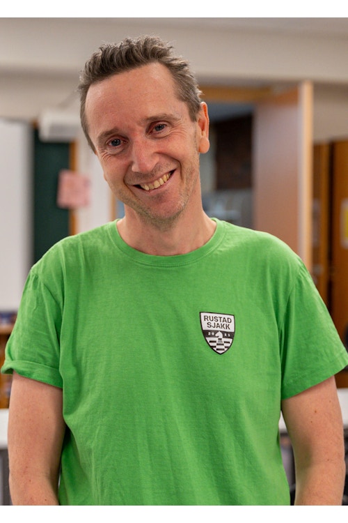 Bilde av sjakktrener Torstein Bae i en grønn t-skjorte med logoen til Rustad Sjakk på brystet.