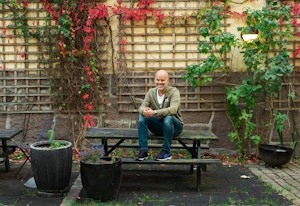Foto av avdelingsleder Christoffer Stange som sitter på en benk på utsiden av boligtilbudet i Pilestredet.