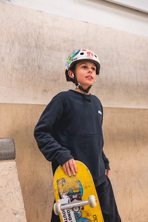 Foto av en gutt som holder skateboardet sitt og mens han ser utover Oslo Skatehatt