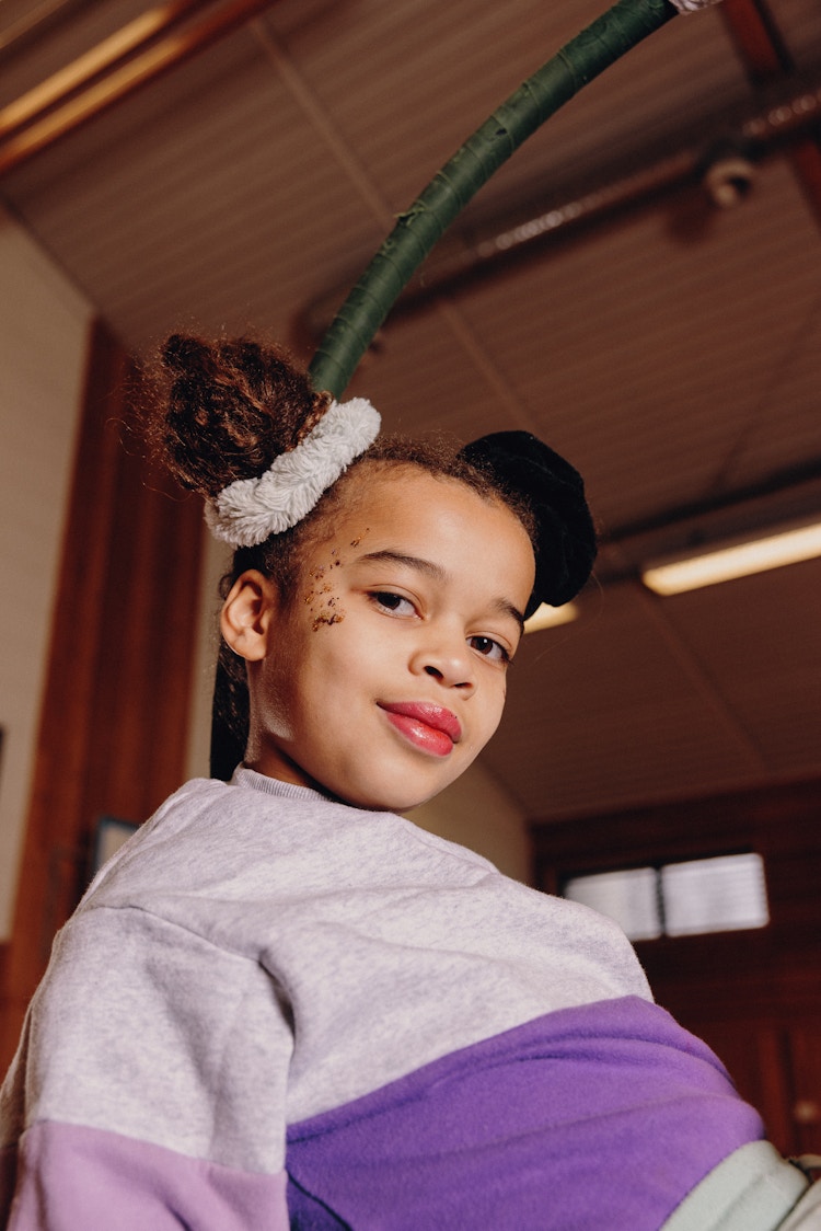 Nærbilde av en ung akrobat. Hun har lilla genser og lilla strikk i håret.