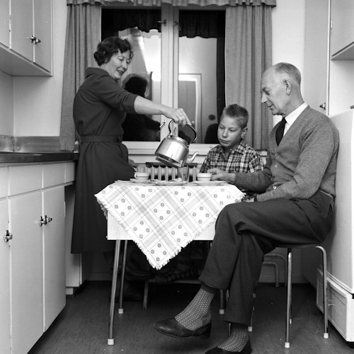 Historisk bilde av Einar Gerhardsens familie på tre som sitter på kjøkkenet