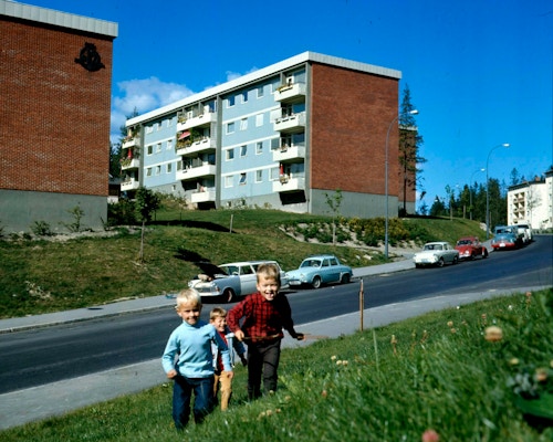 Historisk bilde av borettslag på Lambertseter med tre barn som leker i gresset