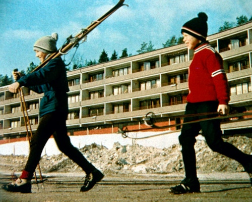 Historisk bilde av to gutter som bærer på et par ski