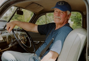 Thormod sitter inne i en av veteranbilene sine, Han har på seg en blå t-skjorte og en blå caps.