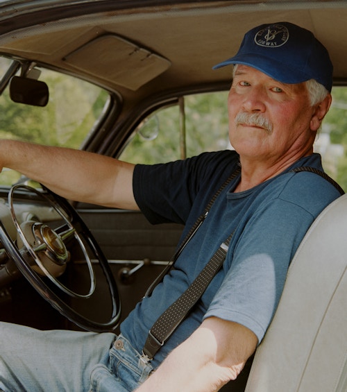 Thormod sitter inne i en av veteranbilene sine, Han har på seg en blå t-skjorte og en blå caps.