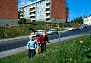 Arkivfoto fra Lambertseter med barn som løper i gresset foran noen blokker.