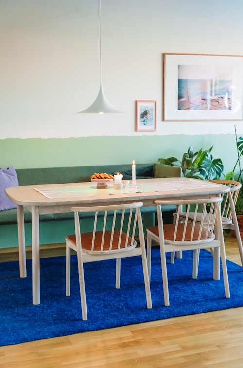 Spisebordet til Ane Engelstad foran en todelt vegg, malt i hvitt fra midten og opp mot taket, og i pistasjgrønn fra midten og ned til gulvet.