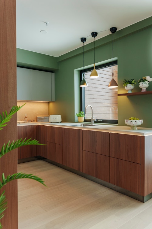Kjøkkenet til Elsa og Tore Moen. Det er moderne med grønne vegger og nøttebrune skap og benker.