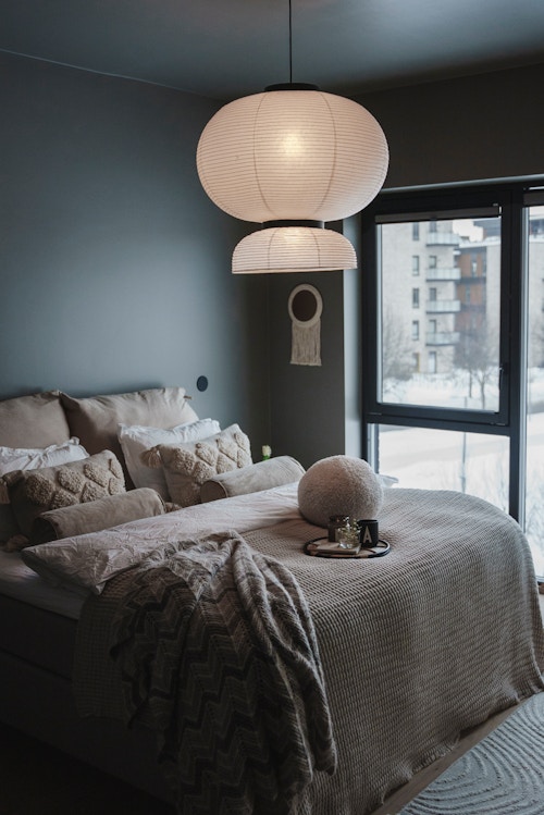 Bilde av et soverom med en beigekledd seng og taklampe av rispapir