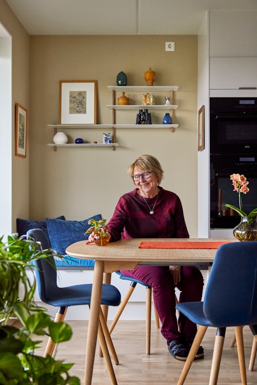 Marit Helene Holen sitter på stol på kjøkkenet sitt i leiligheten på Ulven T.