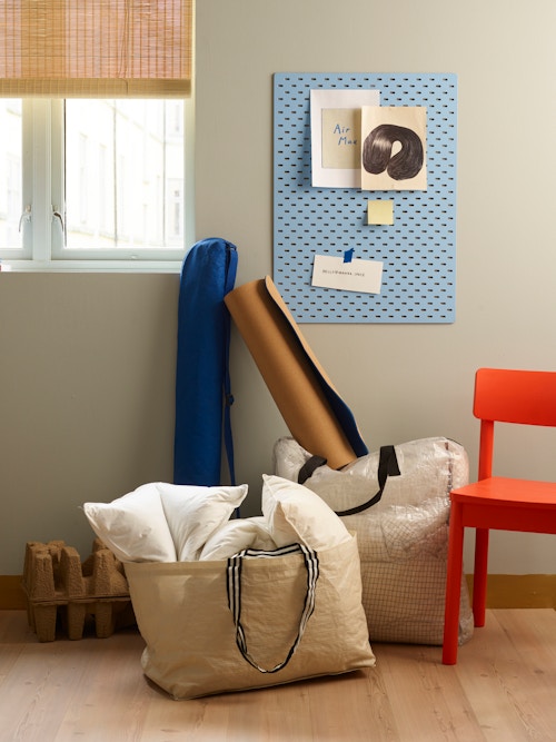 To store oppbevaringsposer fylt med puter og diverse, samt en rød stol og en tavle man kan henge ting på på veggen.