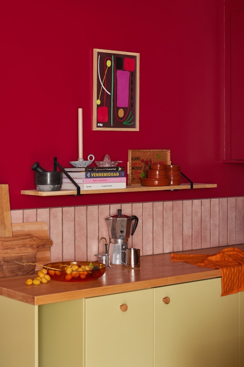 Bilde av kjøkkenet til Elena. Frontene er gule og veggen er rød.