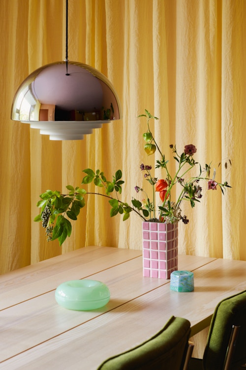 Bilde av spisebordet med en takpendel hengende over. På bordet står det en vase med blomster.