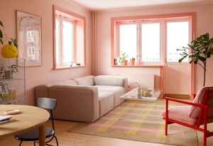 Rosa stue med rosa lister og ulike stuemøbler som beige sofa og rød/rosa stol.