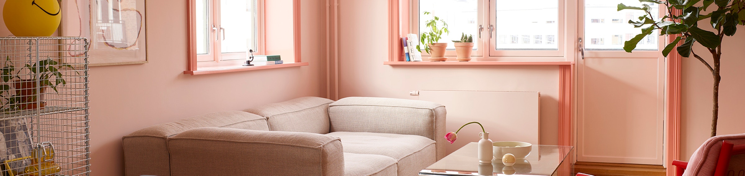 Rosa stue med rosa lister og ulike stuemøbler som beige sofa og rød/rosa stol.