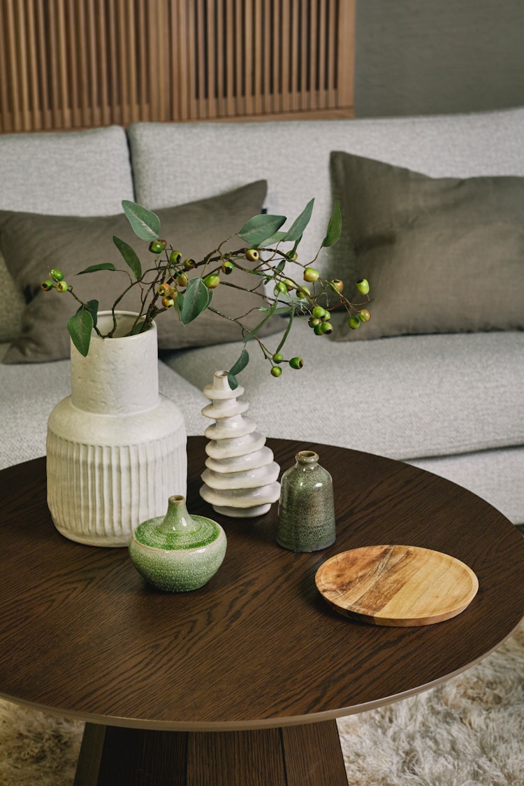 Bildet viser ulike skulpturelle vaser og lysestaker på et stuebord.