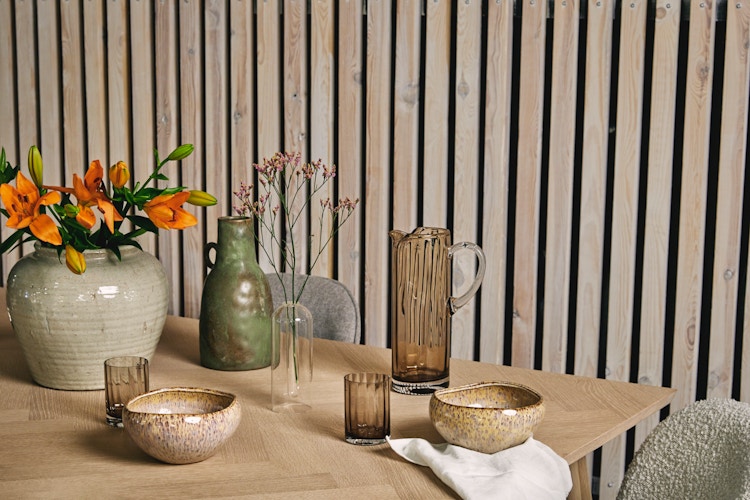 Bildet viser et bord dekket bord med servise, linservietter og blomsterbukett.