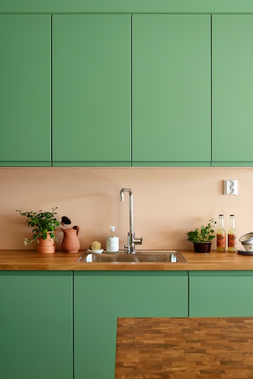 Bildet viser grønne overskap, benkeplate i heltre og grønne underskap på kjøkkenet.