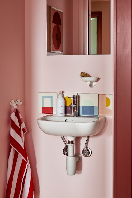 Bildet viser en vask og et speil i det rosa gjestetoalettet.