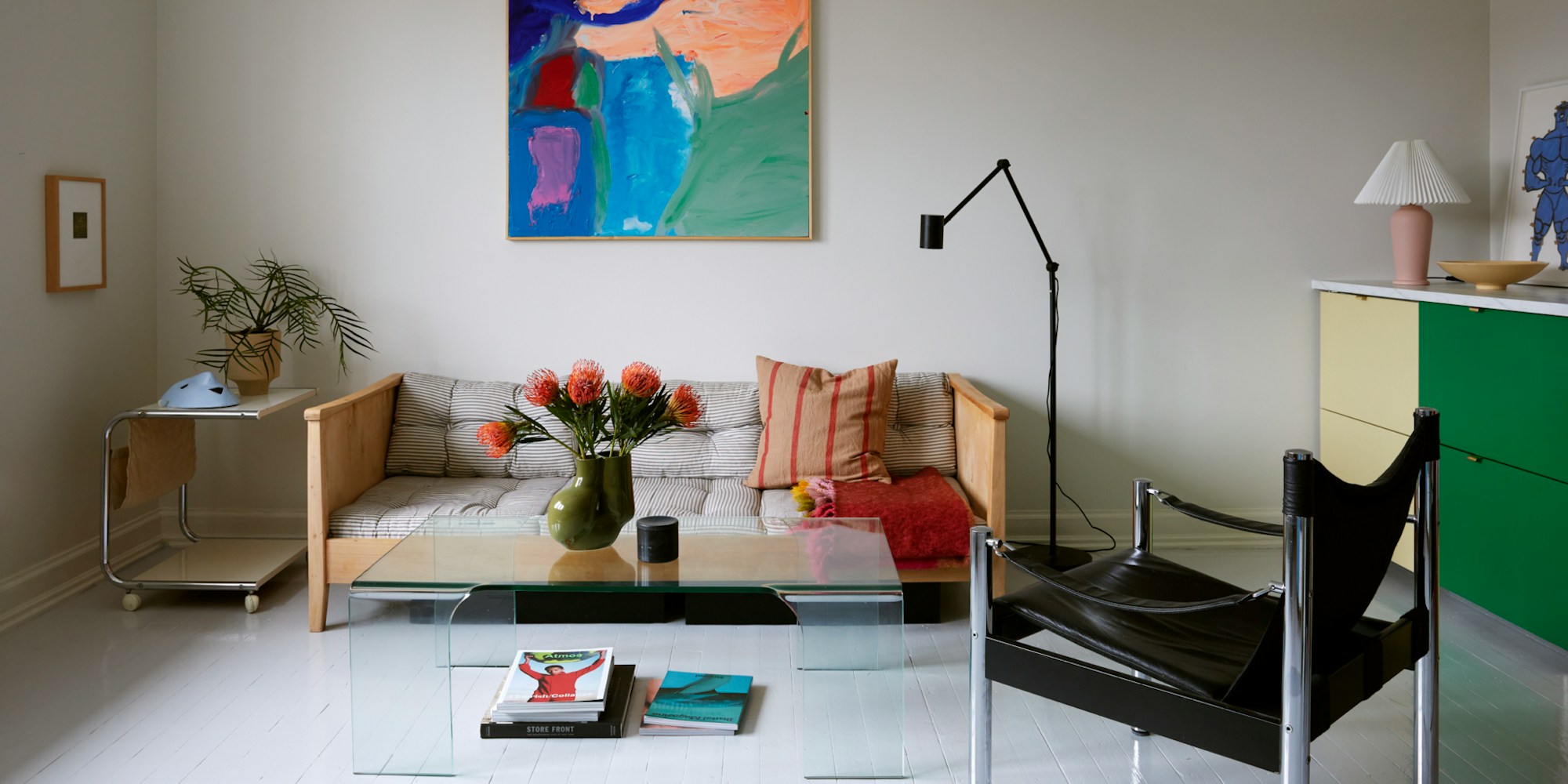Bildet viser en stue med hvitmalt gulv og møbler i ulike farger og fasonger.