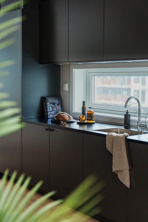 Nærbilde av et sort kjøkken med et vindu som ser ut på fellesområdene i MIDT.