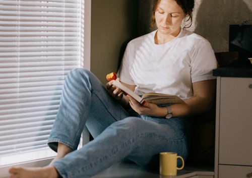 Foto av kvinne som leser en bok i en kjøkkenkrok i OBOS Living Lab