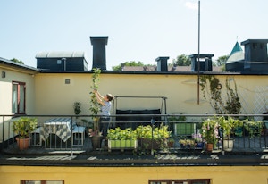 En dame steller en plante på balkongen sin.