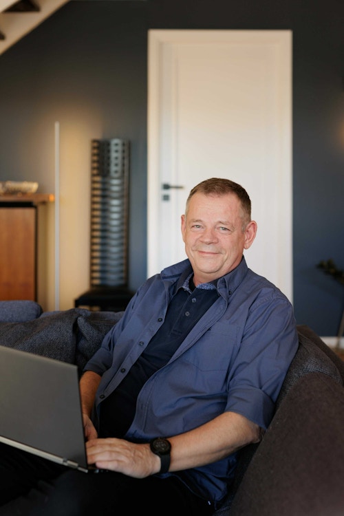 Styreleder Jorulf Breitland jobber med styrearbeid fra sofaen i stuen sin, og med laptop i fanget.