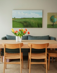 Et bilde av spisebordet i leiligheten på Vitigrend. På veggen henger det to malerier i grønnfarger.